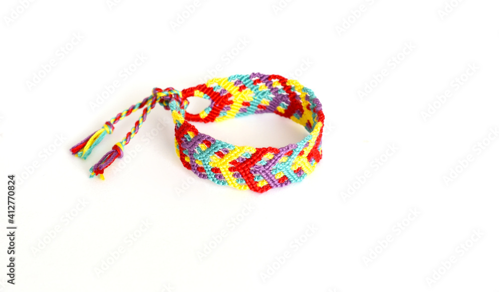 Tied woven friendship bracelet with bright colorful pattern handmade of thread on white background Tied woven friendship bracelet with bright colorful pattern handmade of thread on white background