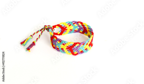 Tied woven friendship bracelet with bright colorful pattern handmade of thread on white background