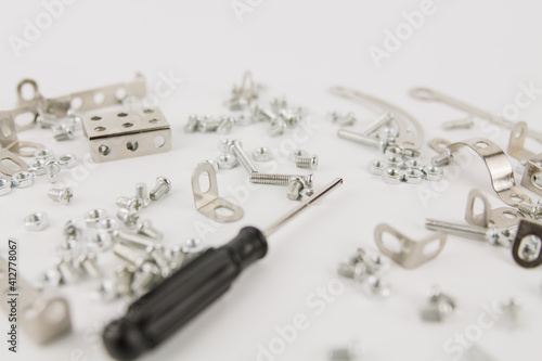 children's iron constructor with nuts and screws and a screwdriver on a white background