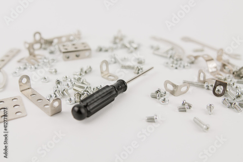 children's iron constructor with nuts and screws and a screwdriver on a white background