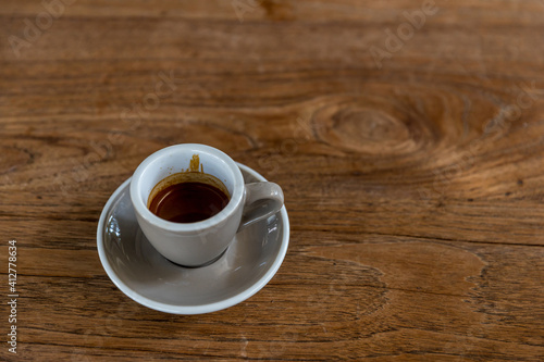 black drip coffee in glass cup. Cup of espresso coffee. Grey cup of black coffee on grey wooden desk or table.