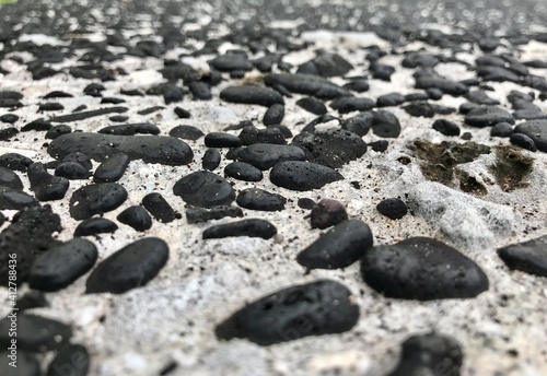 Closeup picture of a pathway made with black lava stone pebbles, pictured from the beach in Moroni Island