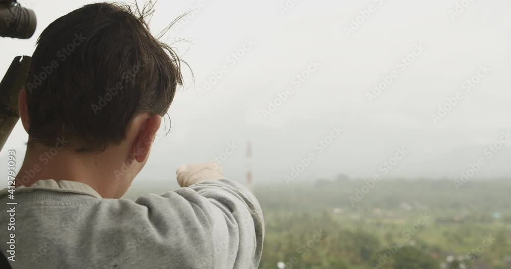 Close up shot of a man on a viewpoint pointing at the panoramic scenery in the rainy valley below in Bali, Indonesia Close up shot of a man on a viewpoint pointing at the panoramic scenery in the rainy valley below in Bali, Indonesia