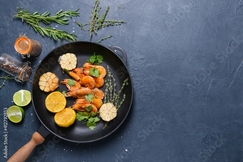 Frying pan with tasty shrimps on dark background