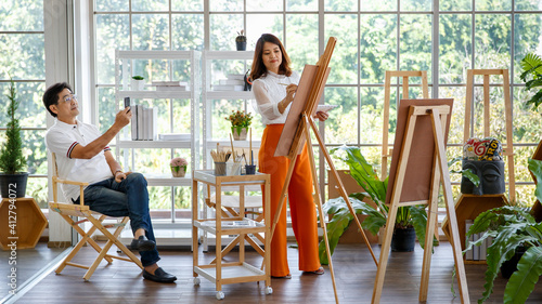 Foto Senior woman artist painting image in studio at home with green small tree in little garden and full of natural light