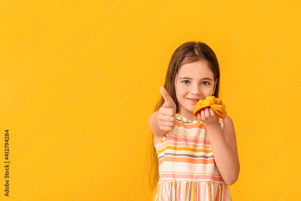 Cute little girl with fresh mango showing thumb-up gesture on color background Cute little girl with fresh mango showing thumb-up gesture on color background