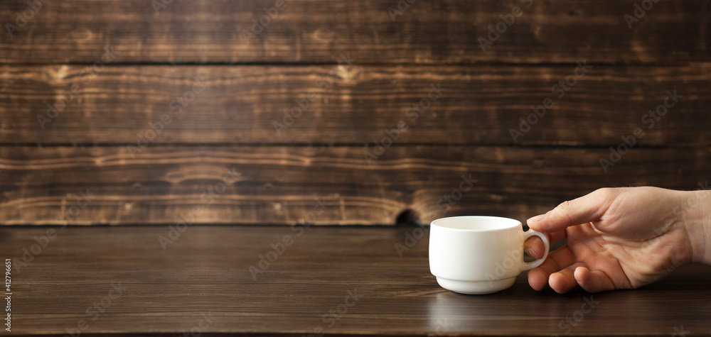 White cup for coffee in hand. On a wooden background White cup for coffee in hand. On a wooden background