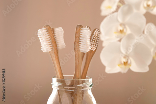Close-up of bamboo toothbrushes in a glass with flowers in the background