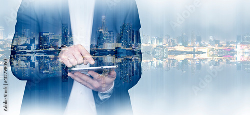 Double exposure of businessman using the tablet with cityscape