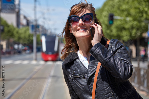Woman using cellphone on a tram station in Europe.