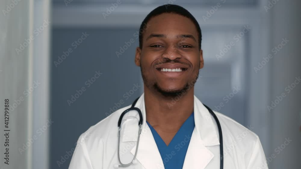 Young african american doctor smiling at camera, standing in hospital interior, close up portrait Young african american doctor smiling at camera, standing in hospital interior, close up portrait