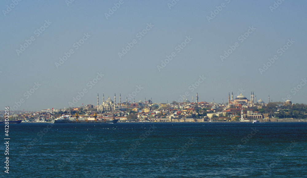 A panoramic shot of a scenery that captures a sea near a path full of buildings and mosque under the sky. This view is from Istanbul, Turkey.