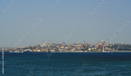 A panoramic shot of a scenery that captures a sea near a path full of buildings and mosque under the sky. This view is from Istanbul, Turkey. © photograzon