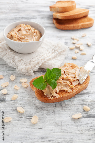 Peanut Butter Sandwich. Decorated with mint. In the background is a cup with peanut butter and bread. Gray wooden background. Close-up.