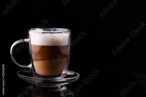 Cappuccino coffee in a transparent cup on a black background.
