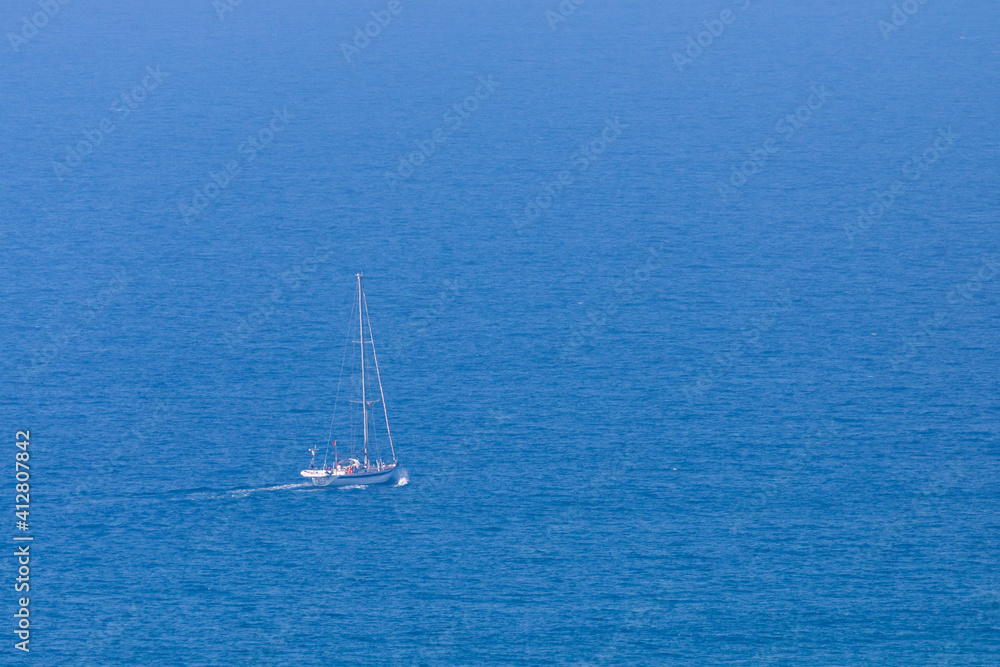White sail boat on blue water of sea. Minimal composition with copyspace