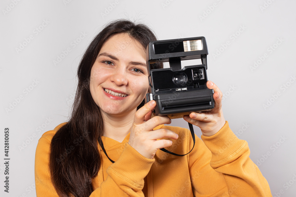 Beautiful lady brunette holds a camera and takes pictures, smiling on a white background. Female photographer, courses and photography training Beautiful lady brunette holds a camera and takes pictures, smiling on a white background. Female photographer, courses and photography training