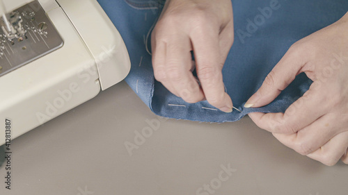 Close-up of woman hands sewing a button. The dressmaker sews a button on a clothes.