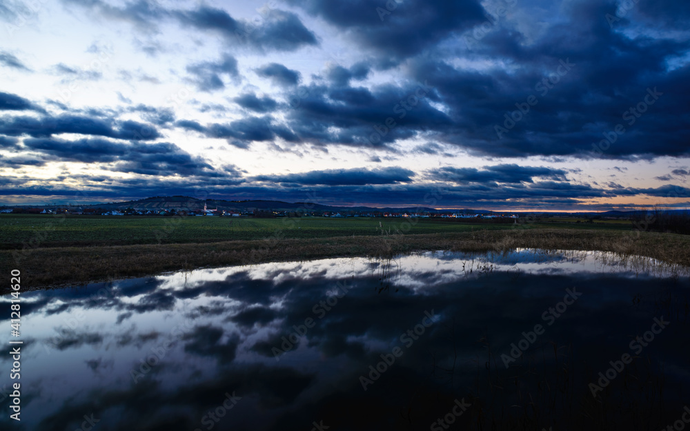 Village of Schützen am Gebirge with reflection in small pond and dark clouds in the morning Village of Schützen am Gebirge with reflection in small pond and dark clouds in the morning