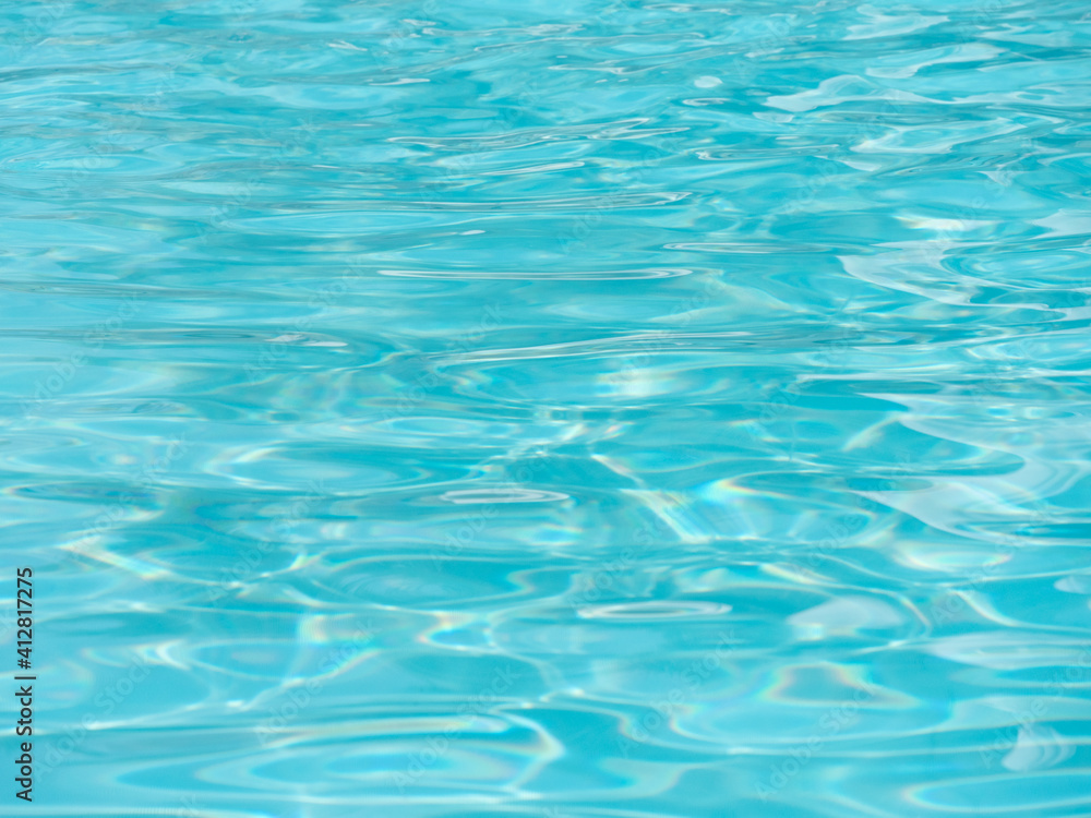 Shiny bright blue water surface in the swimming pool with waves.