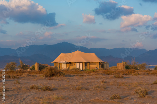 Beige tent  with beautiful sunrise and mountains on the background.  Eco retreat in the mountains. 