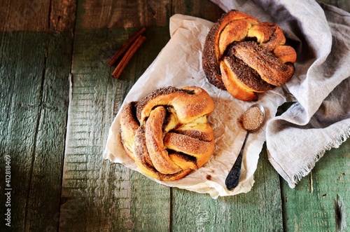 Braided buns with cinnamon on a wooden background, rustic style