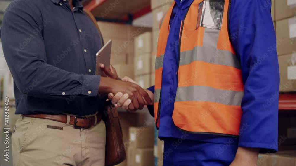 Mid section of warehouse worker and manager shaking hands together in large warehouse Mid section of warehouse worker and manager shaking hands together in large warehouse