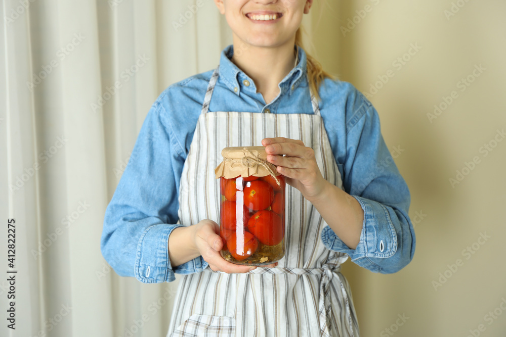 Woman in apron hold jar of pickled tomatoes Woman in apron hold jar of pickled tomatoes
