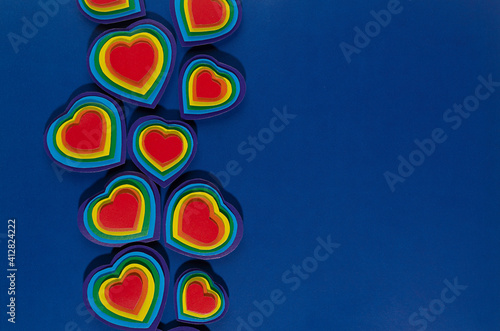 Valentine day background with rainbow hearts on dark blue paper as border, copy space, top view.