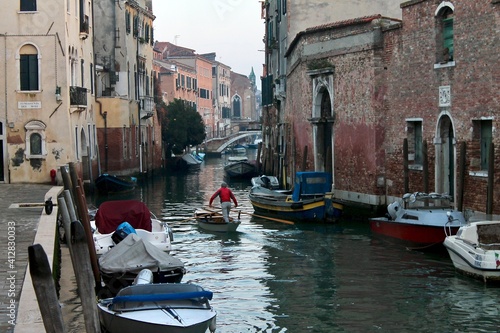 View of a canal with a man rowing in an authentic and residential Venice 