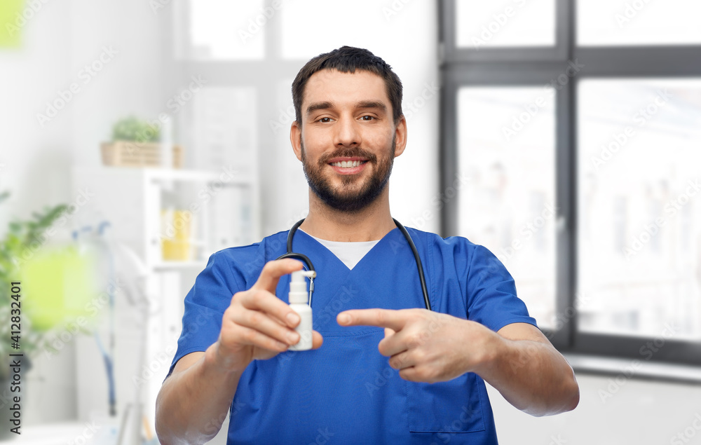 healthcare, profession and medicine concept - happy smiling doctor or male nurse in blue uniform with oral spray and stethoscope over medical office at hospital background healthcare, profession and medicine concept - happy smiling doctor or male nurse in blue uniform with oral spray and stethoscope over medical office at hospital background