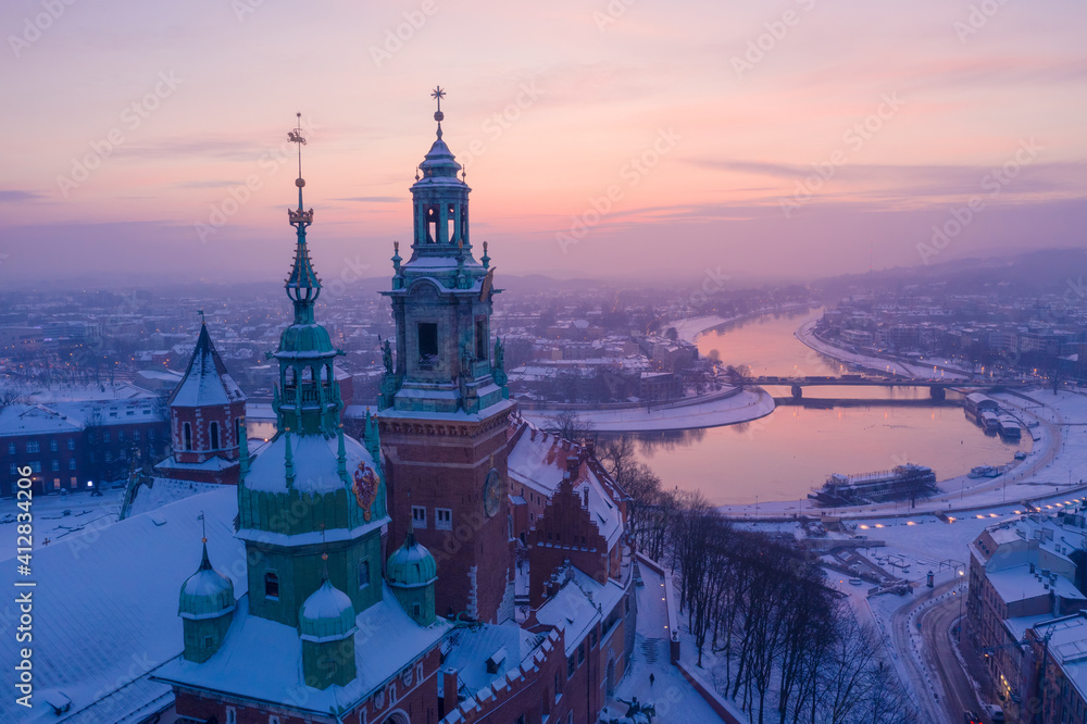 Wawel Royal Castle in winter. Snow on roofs and spires of Wawel castle cathedral and Vistula river in Krakow Poland city center at sunset.