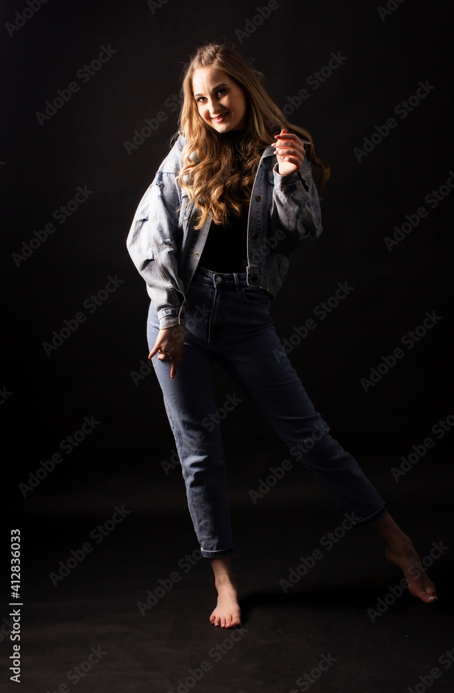 young woman poses with jeans barefoot. Full height, dark background young woman poses with jeans barefoot. Full height, dark background
