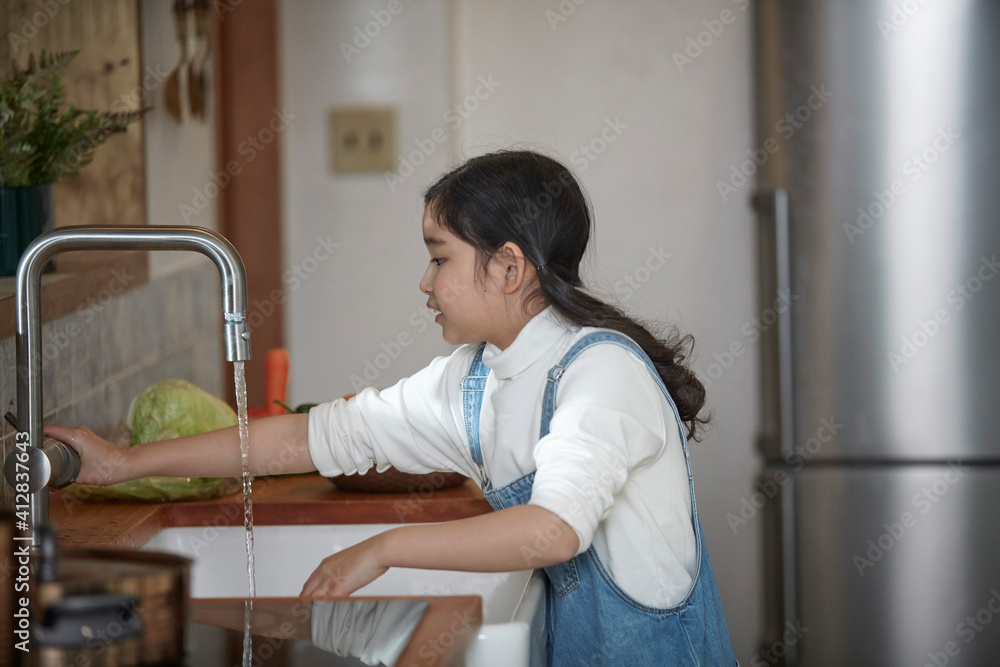 Helping hand. Cute Teenage Girl Help Her Mother In Washing Dishes At Family Kitchen Helping hand. Cute Teenage Girl Help Her Mother In Washing Dishes At Family Kitchen