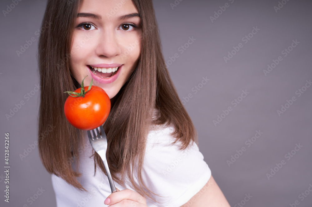 Portrait of a cute girl with a tomato on a fork. Portrait of a cute girl with a tomato on a fork.