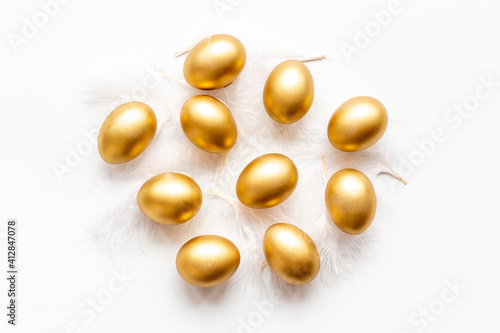 Golden Easter eggs with white feather. Top view decoration