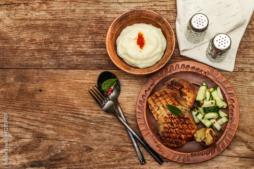 Grilled pork meat with baked garlic, fresh cucumber and mashed potato