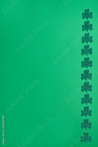 Concept of St. Patrick. Green clovers on green background, top view place for text