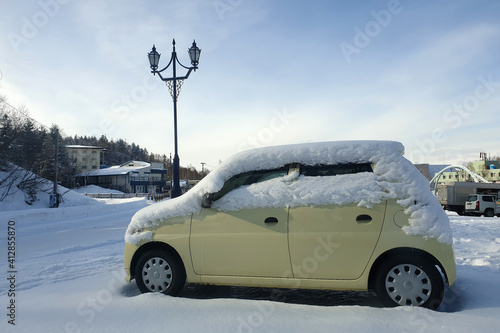 View of a mini car under a thick layer of snow in Biei, Hokkaido, Japan. Biei is a town located in Kamikawa Subprefecture, Hokkaido, Japan. photo