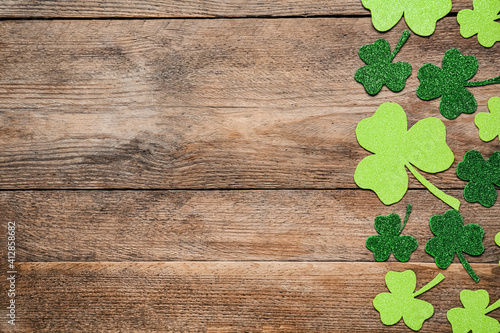 Decorative clover leaves on wooden table, flat lay with space for text. Saint Patrick's Day celebration