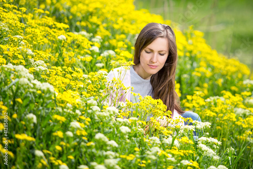 Young woman in blooming park among colorful plants