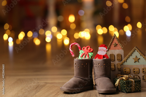 Boots filled with sweets and gift on floor in room, space for text. Saint Nicholas Day
