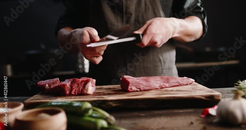 Close up shot of a juicy grilled steak on chef's preparation table. Smoke rising from big piece of tasty meat.