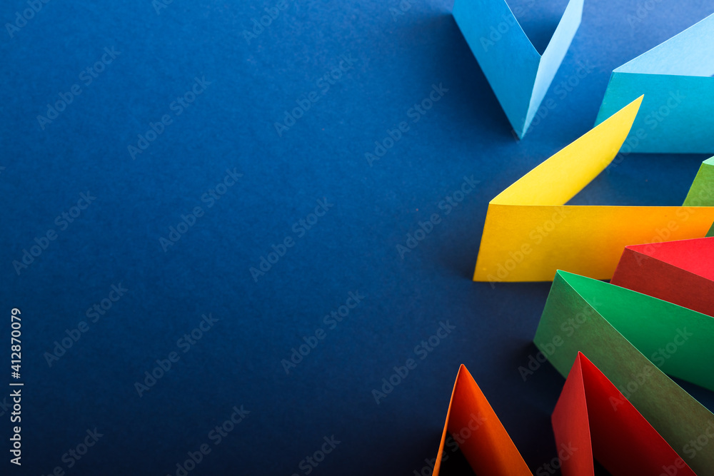 Multicolored cut paper on blue. Abstract arrows, direction signs. - obrazy, fototapety, plakaty 