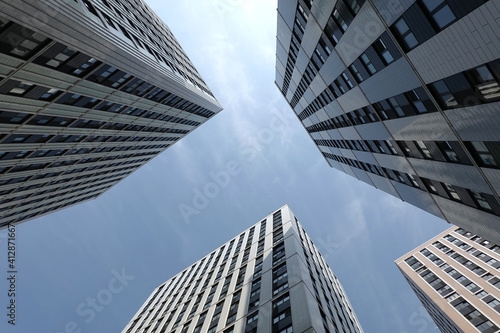 High bottom up perspective view of modern city skyscraper buildings with many windows in the urban cluster
