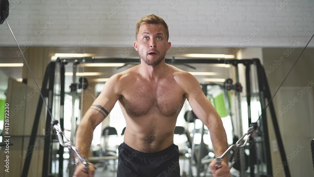 Athlete trains in gym, does exercises in crossover. Slow motion Athlete trains in gym, does exercises in crossover. Slow motion
