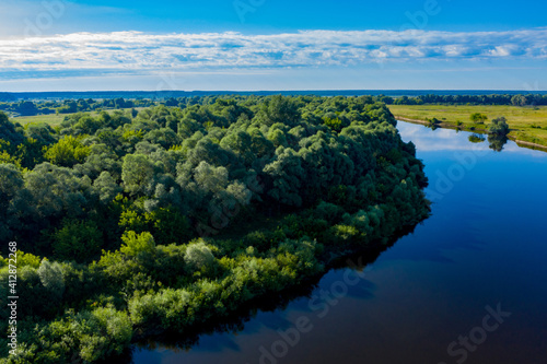 Aerial  view of a beautiful summer  landscape over river while dawn. Top view over river with a smooth water surface reflecting blue sky. © Valua Vitaly