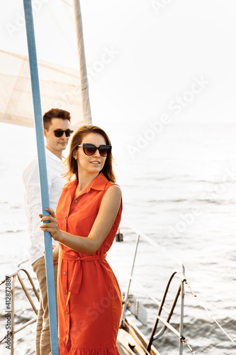 A couple in love on the edge of the yacht hug and hold hands, show love, strong hugs, blue sea, white sailing yacht. Happy valentines day