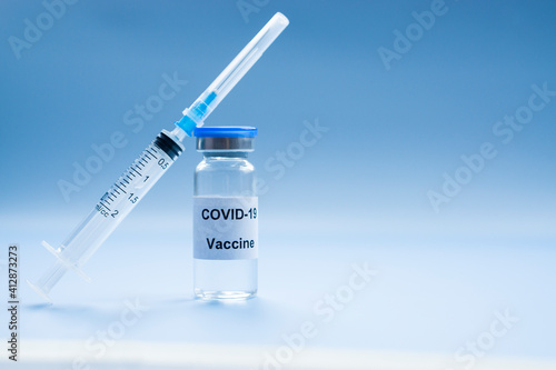 Vial of Covid-19 vaccine with syringe on blue medical background