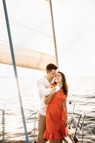 A couple in love on the edge of the yacht hug and hold hands, show love, strong hugs, blue sea, white sailing yacht. Happy valentines day © Александр Шуневич